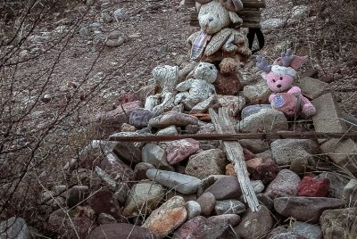 Where Dreams Die Stone cairn bedecked with weathered stuffed animals.