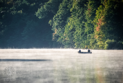 Two anglers out fishing in boat on misty Hudson Lake.
