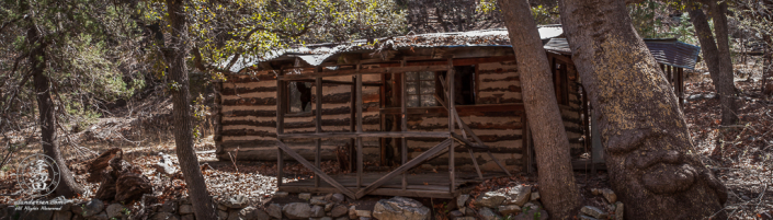 Deserted old log cabin next to creek.