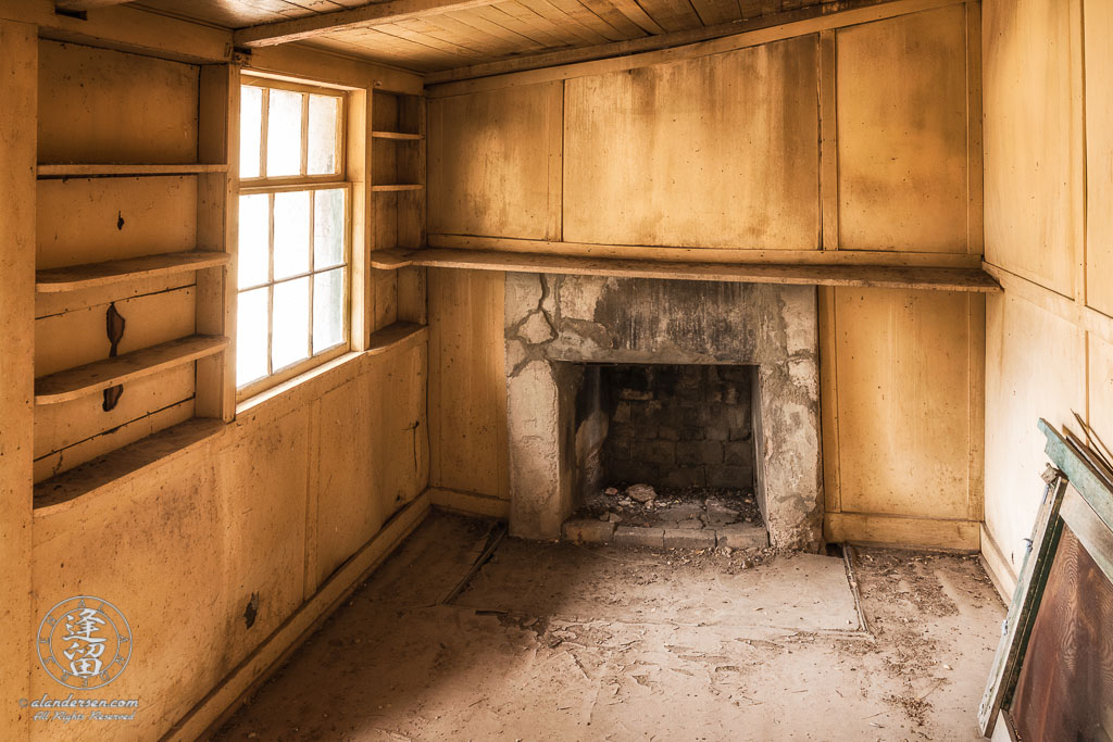 Front room in ranch house at Camp Rucker, Arizona, with wood-paneled walls, fireplace, and built-in book shelves.