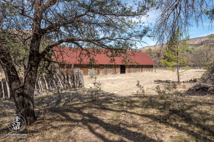 Atockaded barn at historic Camp Rucker seen from beneath trees.