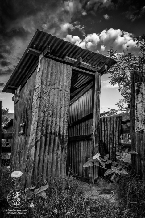 Leaning outhouse made of corrugated tin by Brown Canyon Ranch corrals outside Sierra Vista in Arizona.