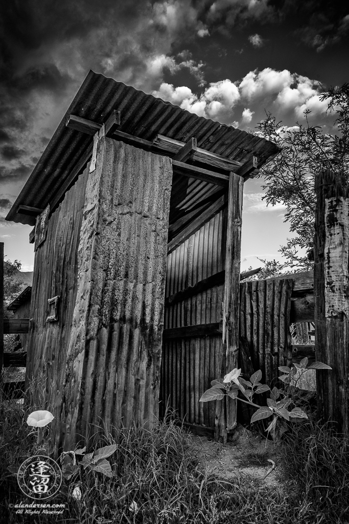 Leaning outhouse made of corrugated tin by Brown Canyon Ranch corrals outside Sierra Vista in Arizona.