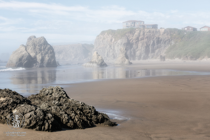 House atop cliffs, seen through the afternoon mists from the beach near Face Rock State Scenic Viewpoint in Bandon, Oregon.