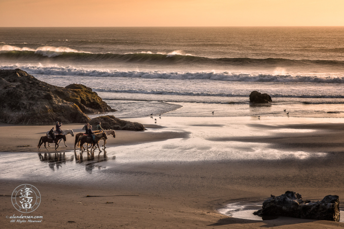 Local horseback riders out enjoying the sunset on Bandon Beach in Oregon.