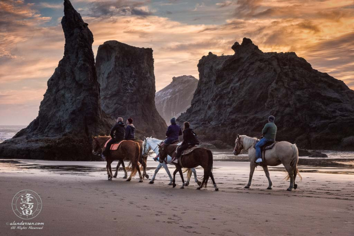 Local horseback riders out enjoying the sunset near Wizard Hat on Bandon Beach in Oregon.