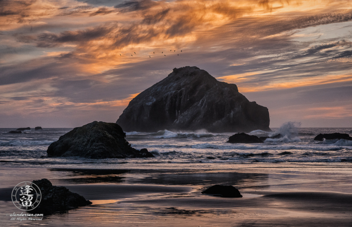 Face Rock in dark silhouette amidst crashing waves during a wonderful sunset at Bandon Beach in Oregon.