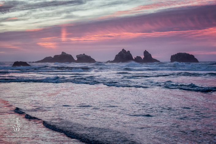Pastel pinks and magentas imbued seascape during sunset near the Cat & Kittens on Bandon Beach in Oregon.