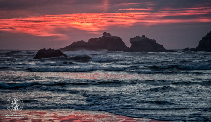 Setting sun casting fiery glow over the Kittens seastacks at Bandon Beach in Oregon.