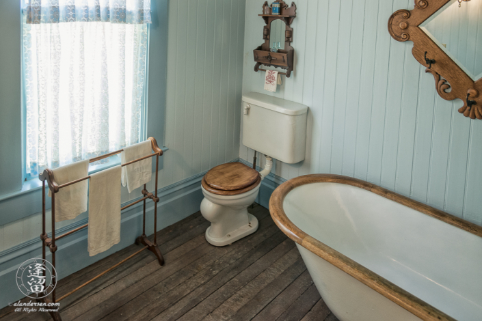 Toilet and wood-trimed claw-footed free-standing bathtub in the Master Bathroom of the Hughes House near Port Orford, Oregon.