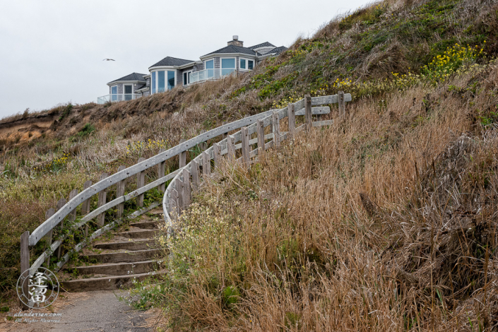 Stairs leading up to the cliff above Bandon beach, between South Jetty County Park and Coquille Point, with a private residence atop the cliff.