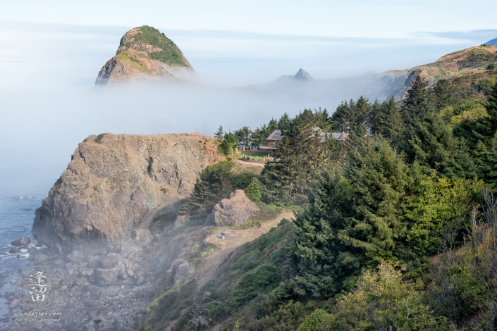 Seastacks floating in morning fog provide a fairy-tale ocean view of a cliff-side home on the Southern Oregon Coast near Ophir.