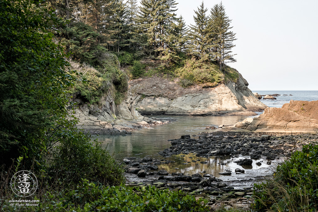A scenic view from the rock-strewn beach at Norton Gulch, which is next to Sunset Bay State Park near Cape Arago in Oregon.