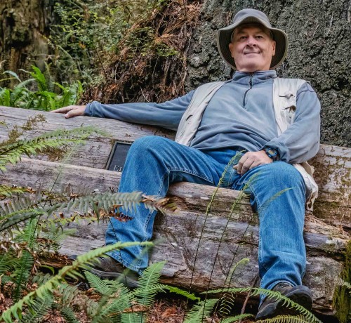 Al Andersen sitting on a redwood log bench.