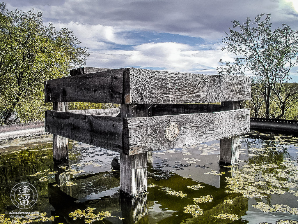 Rraised wooden platform in center of filled steel water tank.