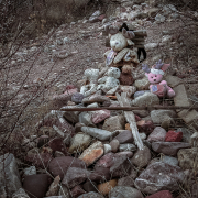 Stone cairn bedecked with weathered stuffed animals.