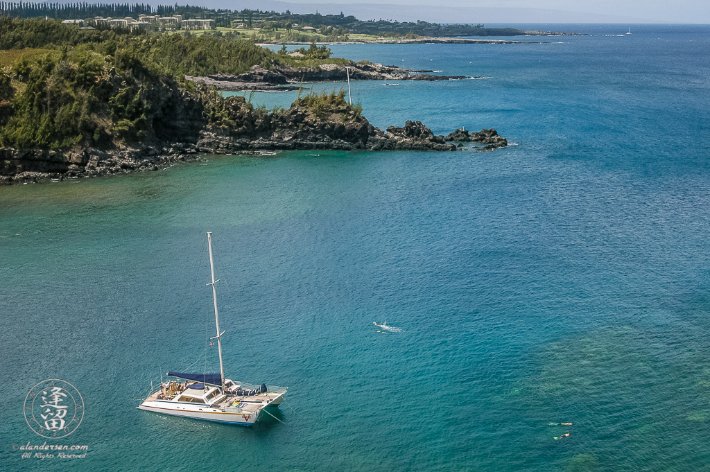 Catamaran anchored in the clear blue waters of Honolua Bay on Hawaiian Island of Maui.