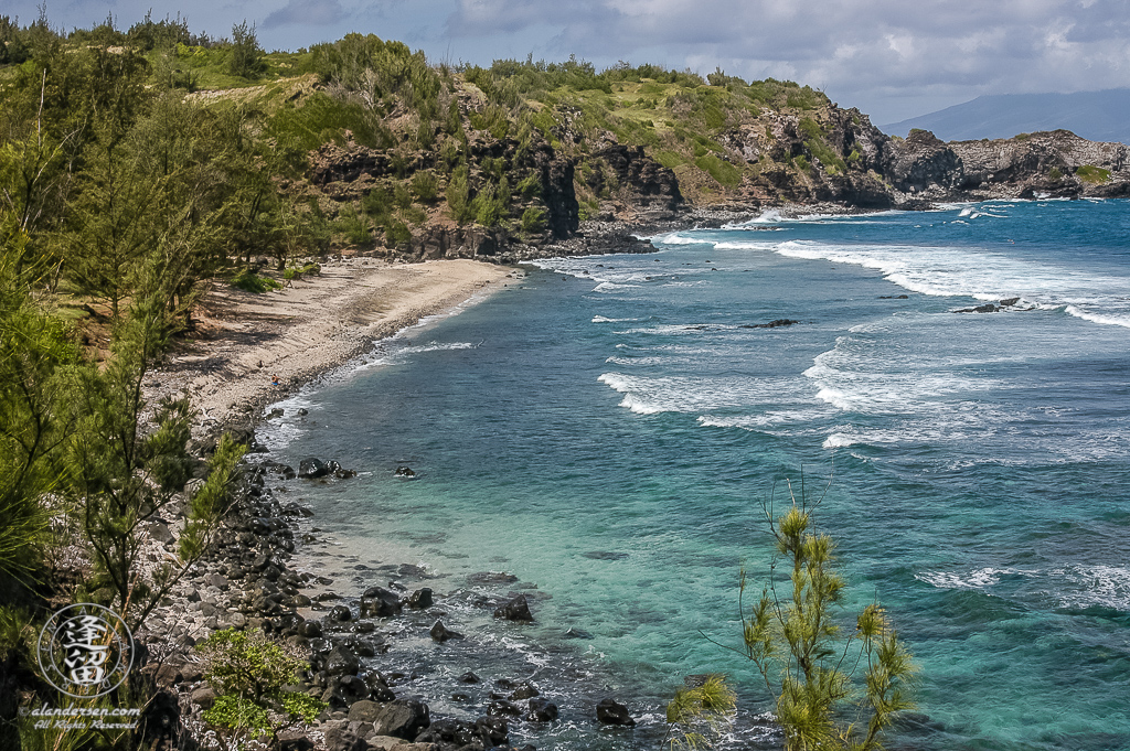 Ocean surf rolling over the clear blue waters of Punalau Beach on the Hawaiian Island of Maui.