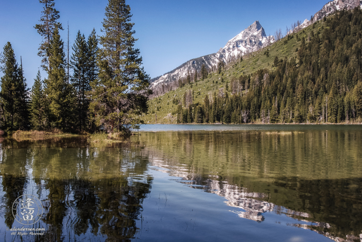 Snow-covered Storm Point peak reflected in String Lake.