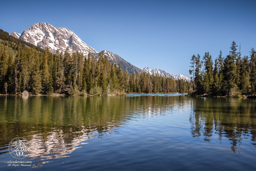 Snow-covered slopes of Mt. Moran reflected in String Lake at Grand Teton National Park.