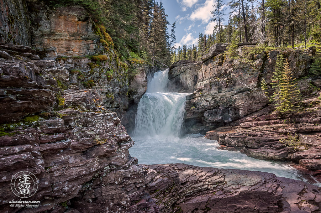 Clear turquoise waters of St. Mary's Falls roaring through a gorge.