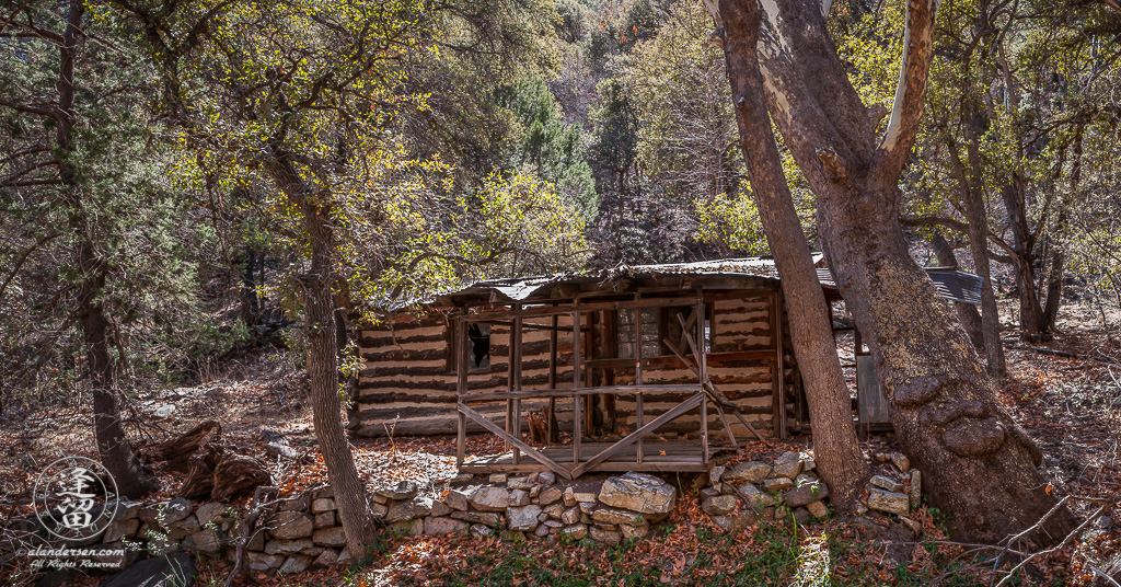 Deserted old log cabin next to creek.