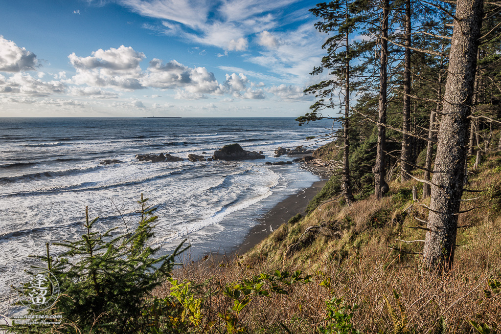 Waves rolling up on narrow shoreline of Washington's Beach 4 beneath a blue sky with white puffy clouds.