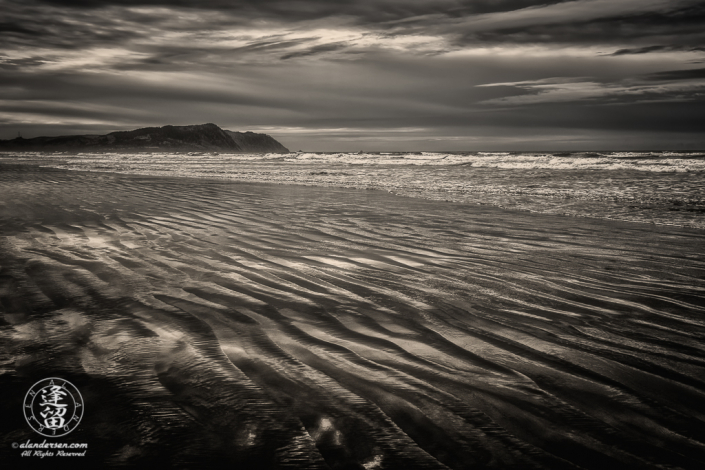 Rippled wet sand reflecting storm clouds from overcast sky at Del Rey Beach State Recreation Site, Oregon.