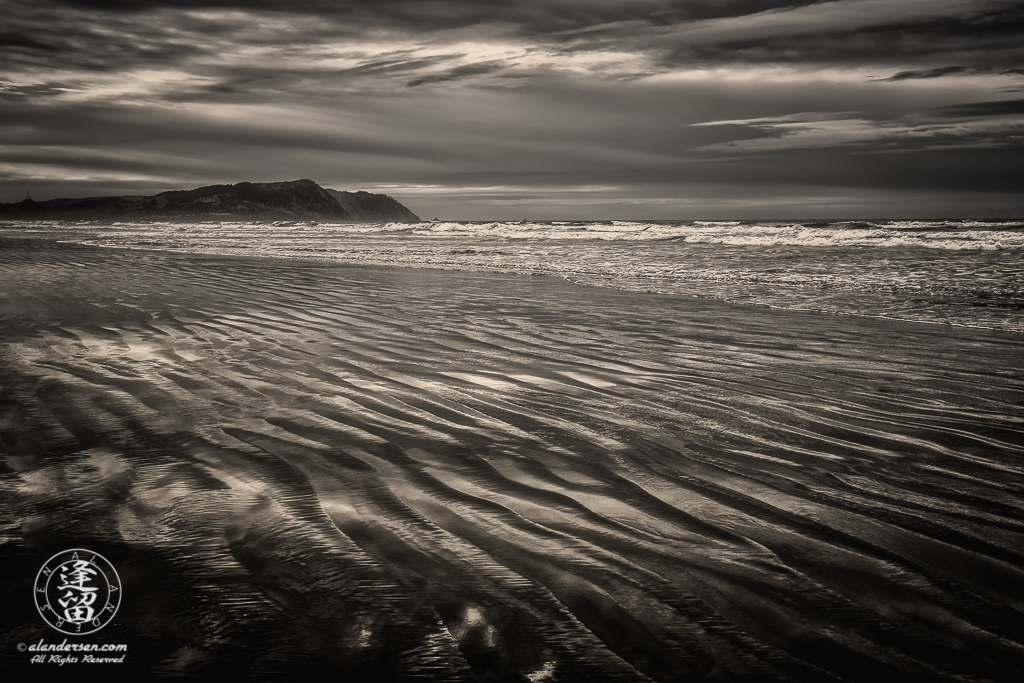 Rippled wet sand reflecting storm clouds from overcast sky at Del Rey Beach State Recreation Site, Oregon.