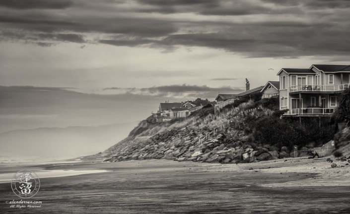 Homes line crumbling sandstone cliffs along sandy beach above Gleneden Beach State Wayside Park in Oregon.