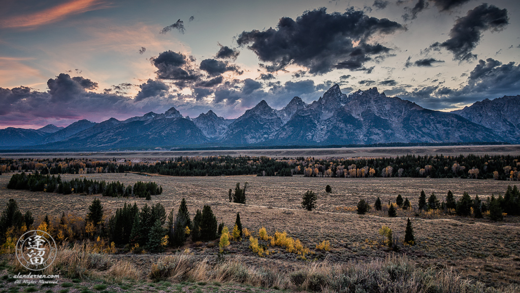 Dark clouds at dusk on Autumn night behind jagged Grand Teton mountains in Wyoming.