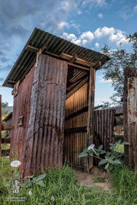 Leaning outhouse made of corrugated tin by Brown Canyon Ranch corrals outside Sierra Vista in Arizona.