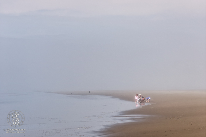 Children exploring the wonders of the beach with their father on a foggy afternoon at Bandon in Oregon.