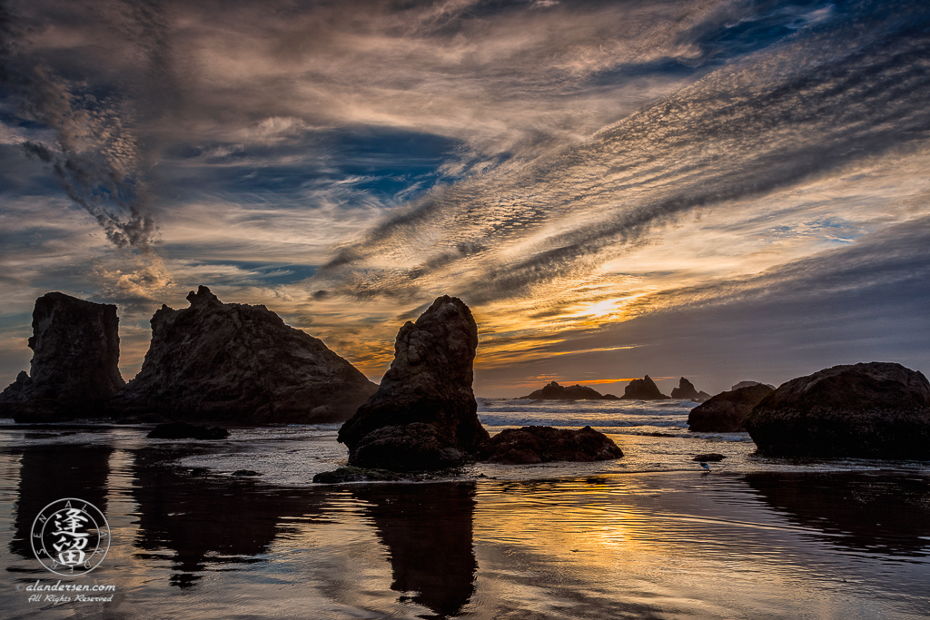 Golden sun obscured by cloud embankment setting over the Kittens at Bandon, Oregon.