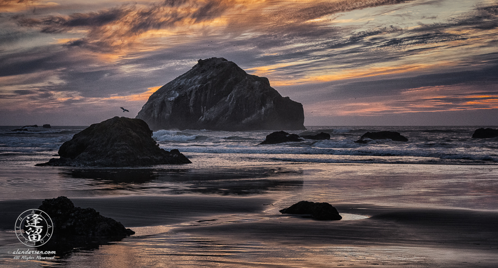 Face Rock in dark silhouette amidst crashing waves during a wonderful sunset at Bandon Beach in Oregon.