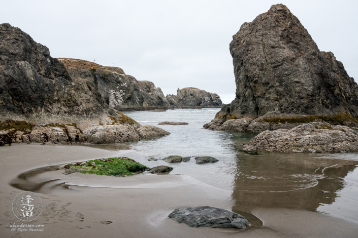 Seastacks reflected in wet sand on the beach near Coquille Point at Bandon in Oregon.